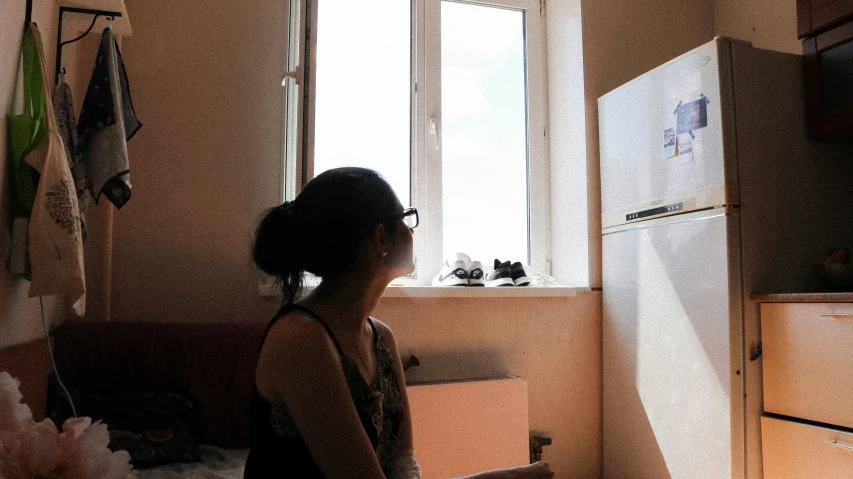 a woman is looking out of a kitchen window