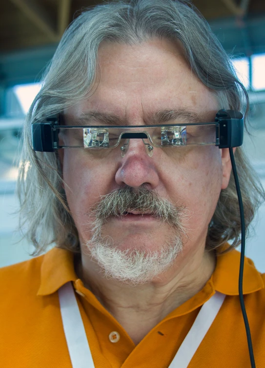 a close - up view of a man wearing glasses and an orange shirt