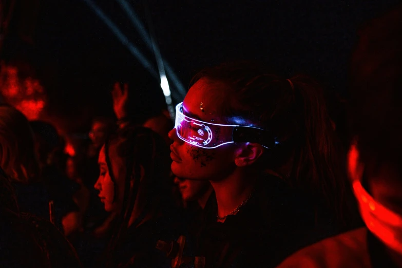 a crowd is wearing glowing glasses at a music festival