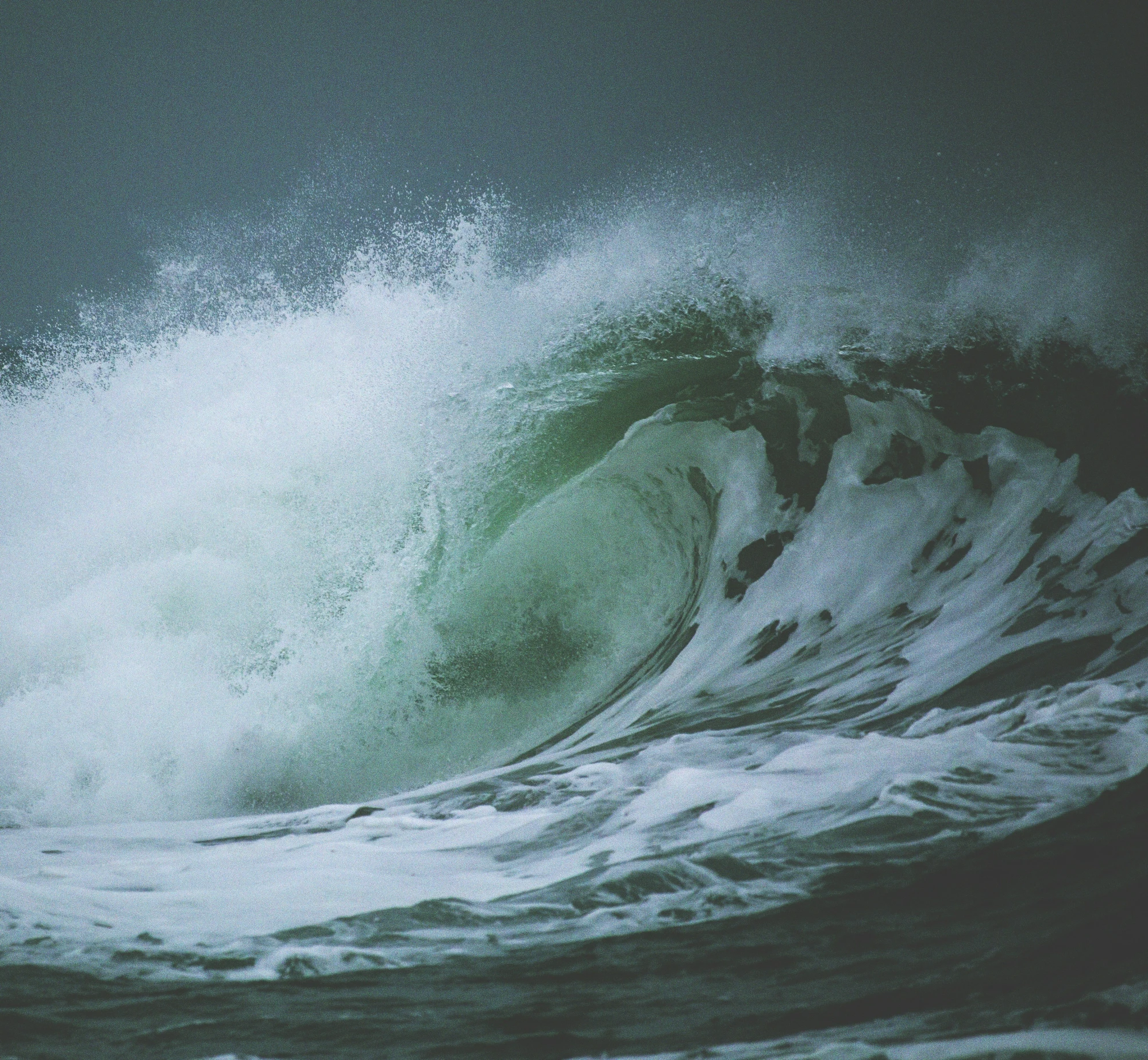 a large wave breaks over the top of an ocean wall