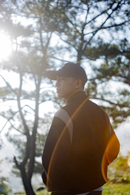 the man is standing in front of a tall tree