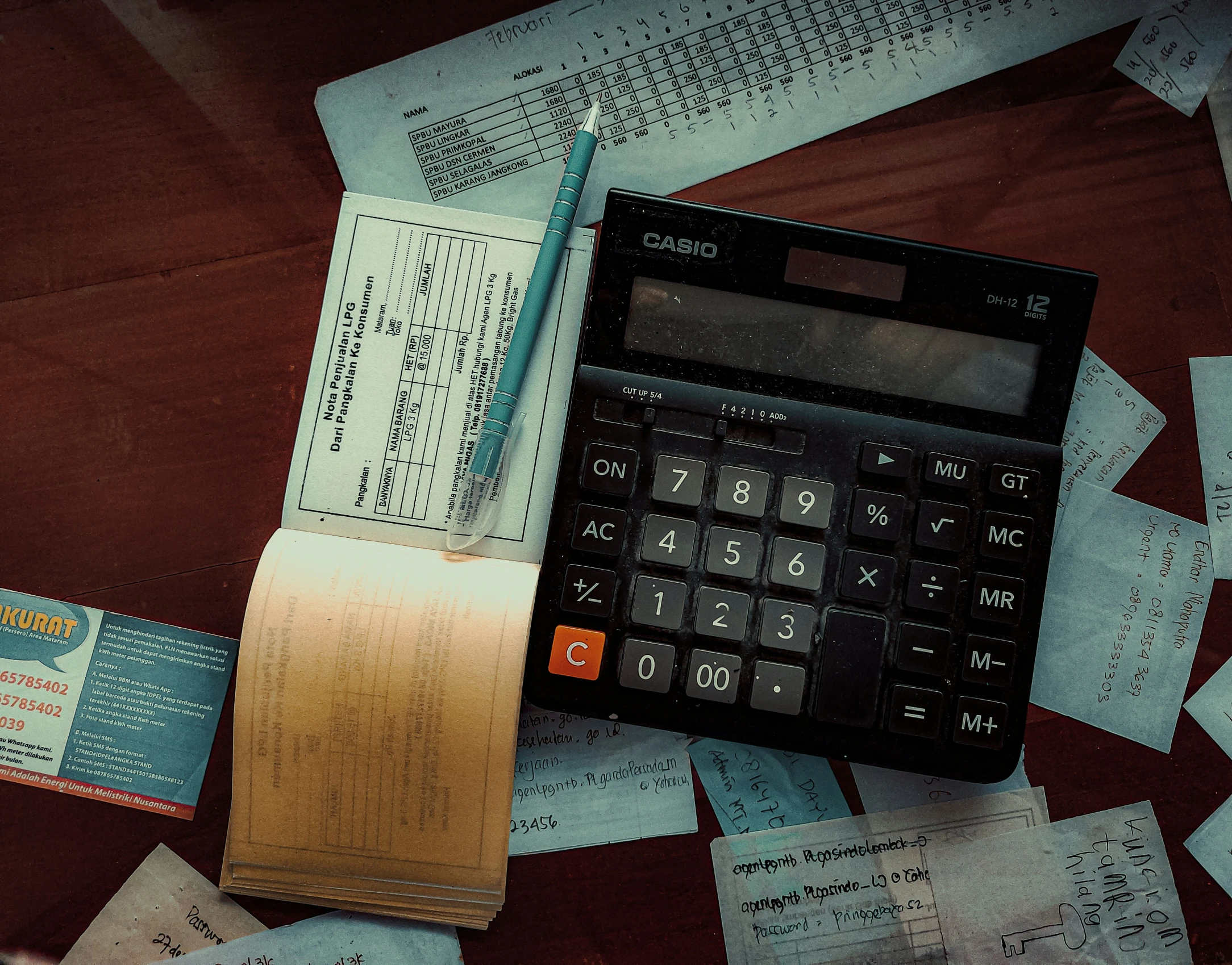 a calculator with many papers on it and a pen on the table