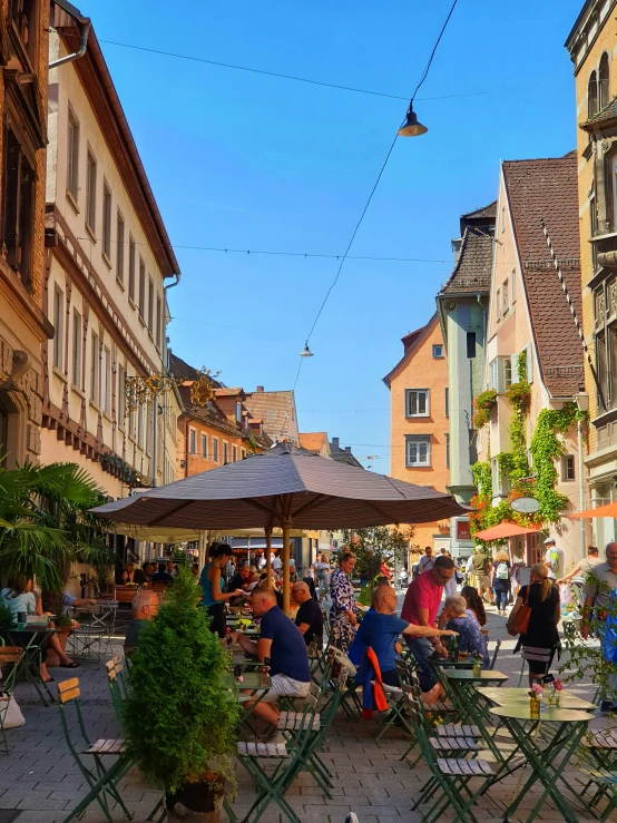 several people sitting at tables and chairs near buildings