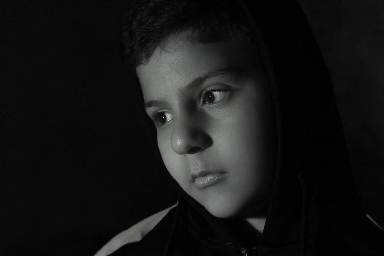 a young man in a hooded sweatshirt stares straight ahead