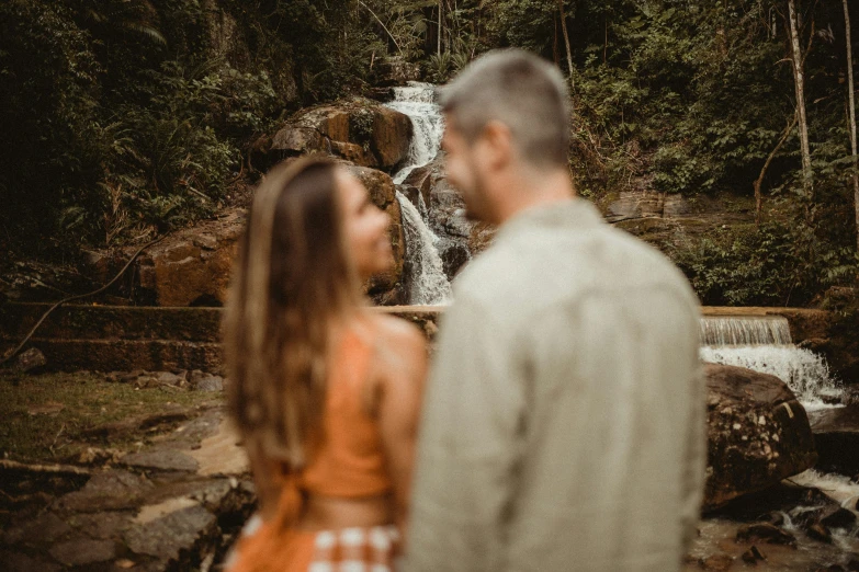 a woman and a man standing in front of a waterfall