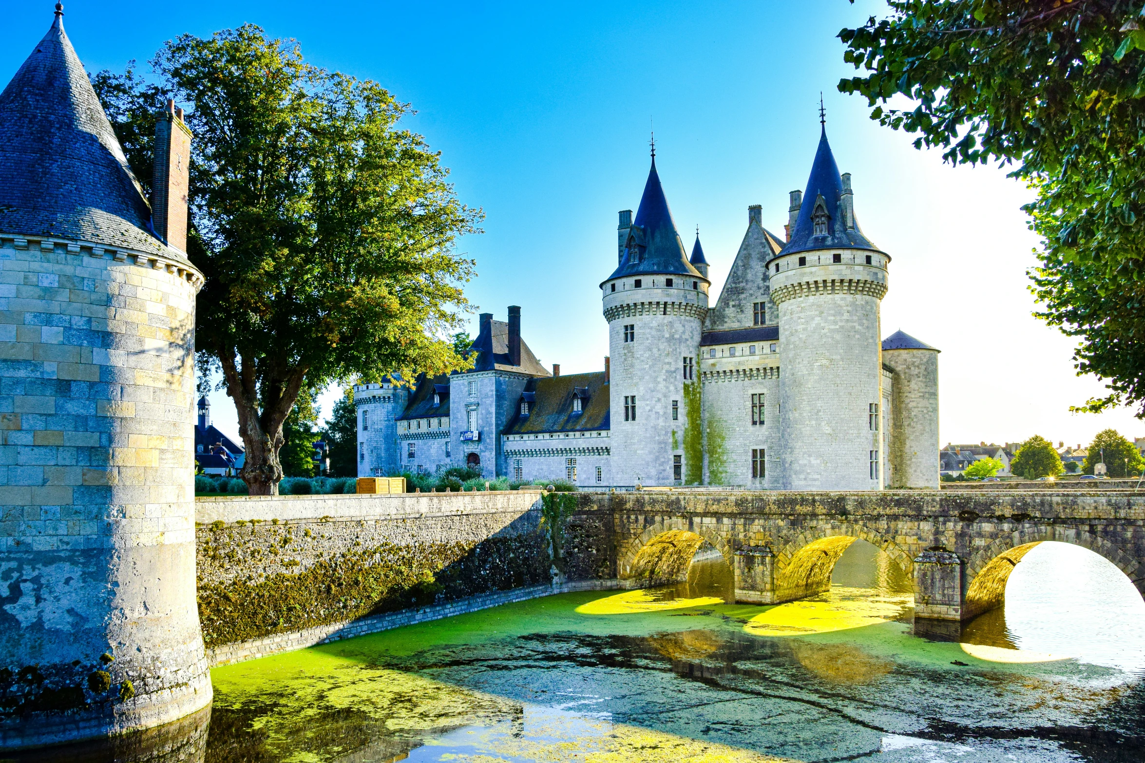 an old stone castle near water under a blue sky