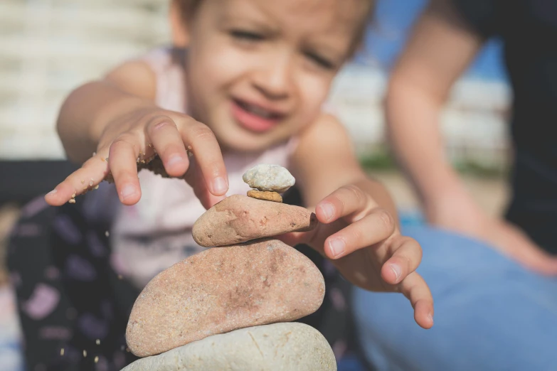 a young child putting a stone on top of other rocks