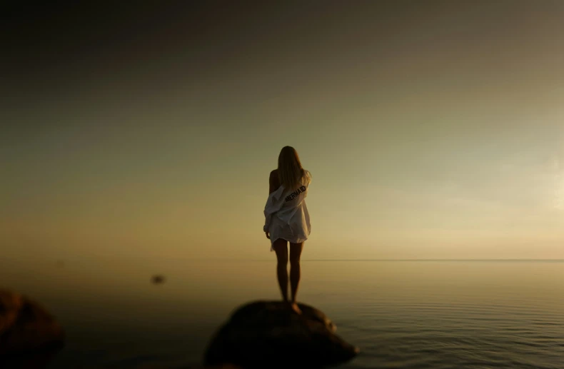 a person standing on top of a rock next to water