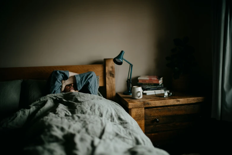 a person sleeping on a bed with an unmade sheet