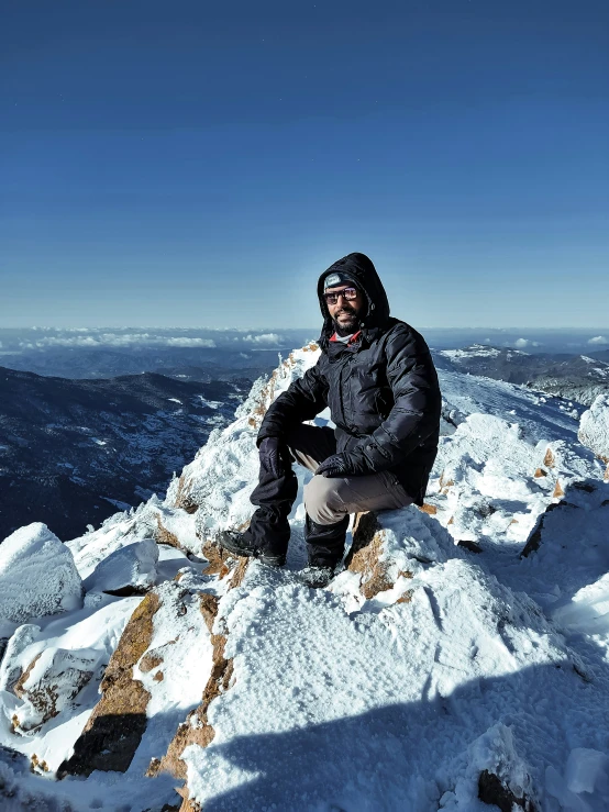 a man sitting on top of a mountain with his feet in the snow