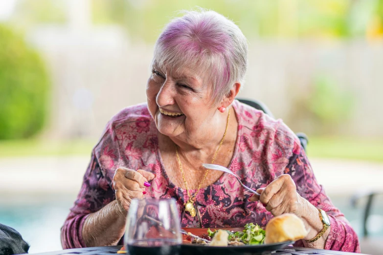 a smiling elderly woman eating at a table