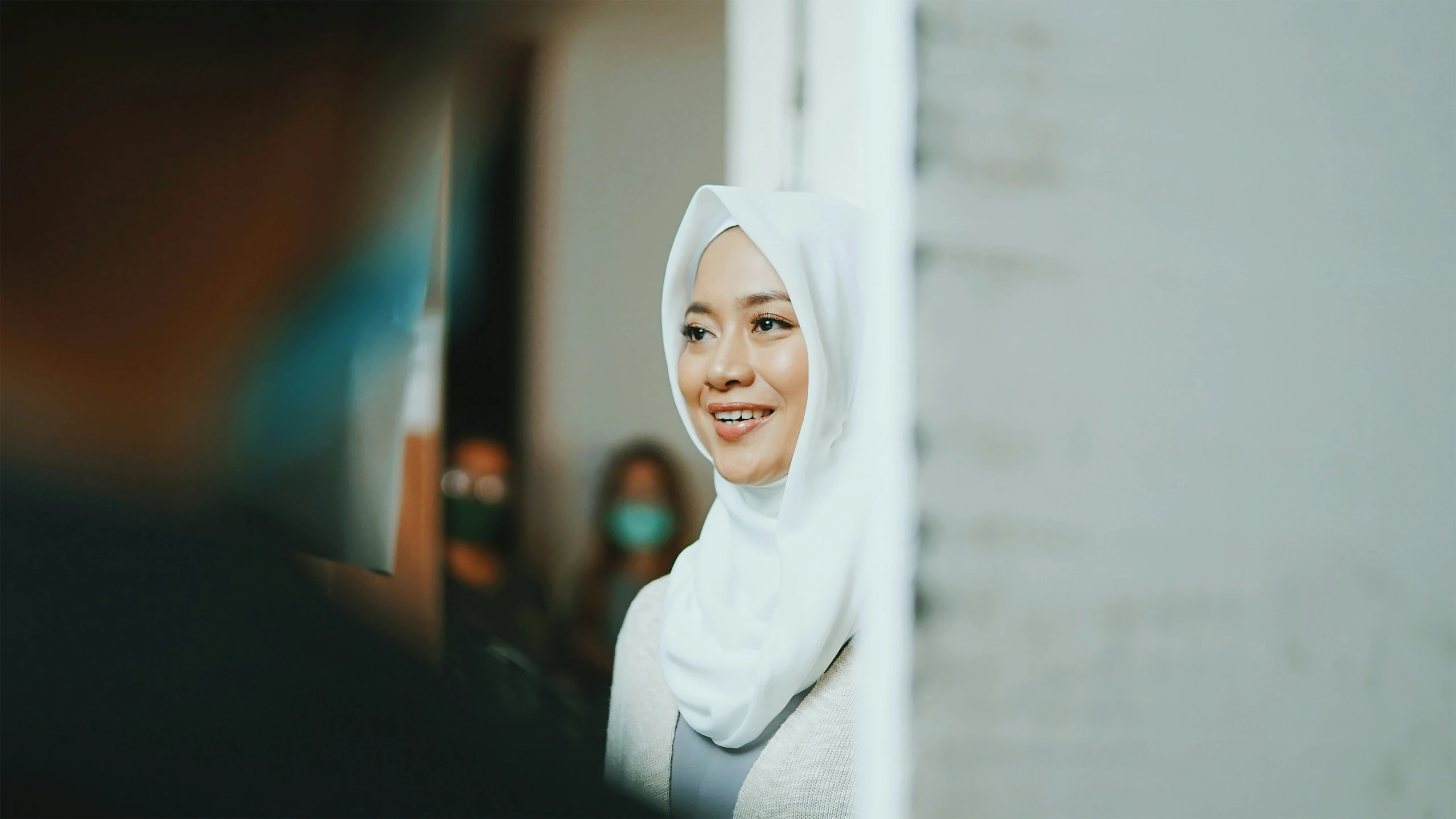a smiling woman wearing a white headscarf