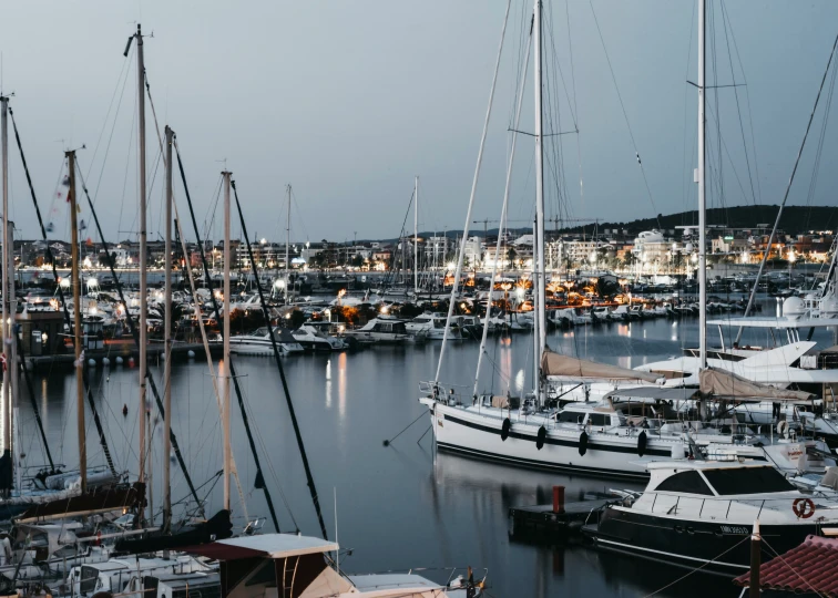 several sailboats are docked in the harbor at night