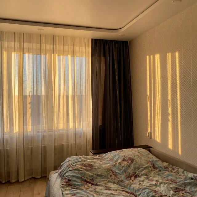 the bedroom has two curtained windows with brown and cream curtains