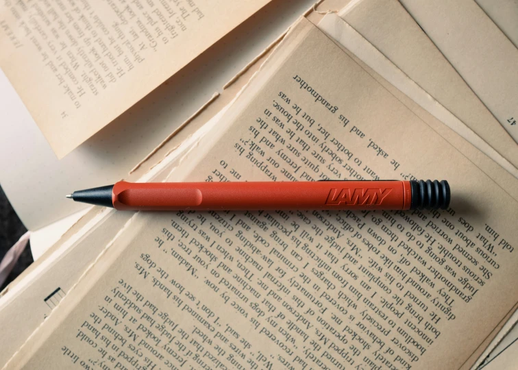 an orange pen is on top of several open books