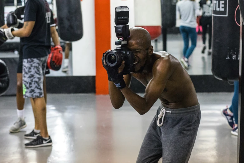 man standing with camera and holding boxing gloves