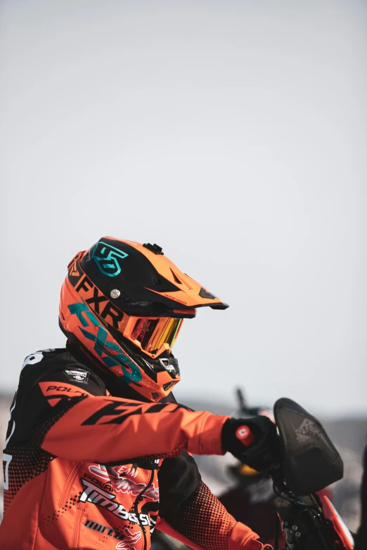 a man with a helmet and orange jacket sits on a motorcycle