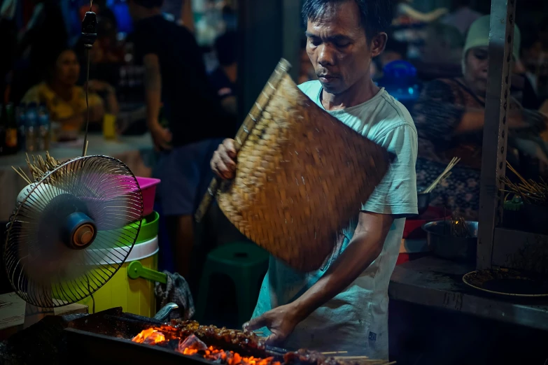 a man holding a large basket near an open fire