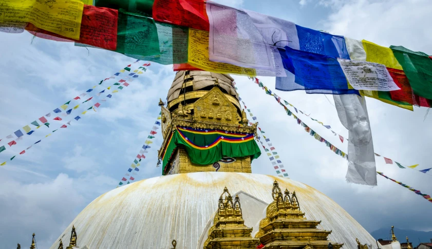 many multicolored banners hang in front of a domed structure