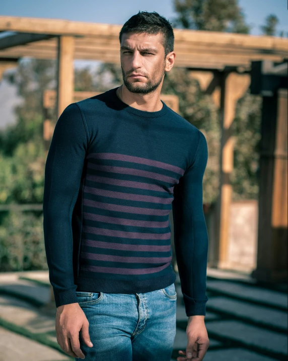 a young man is standing wearing blue and black stripes