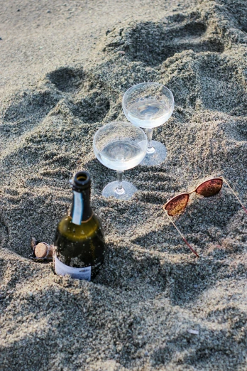 empty wine bottles lie on a sand covered beach