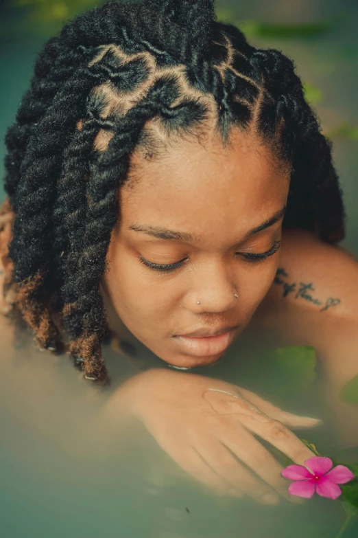 a close up of a woman in water with a flower