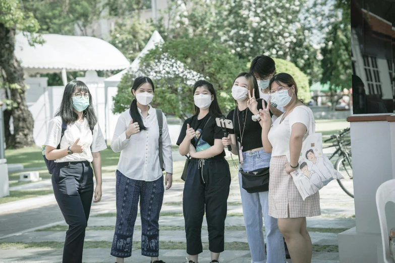 four girls are wearing masks standing outside