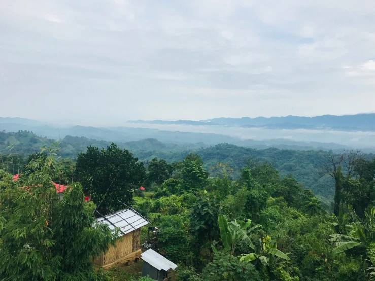 a rural area overlooking mountains and clouds with a hut