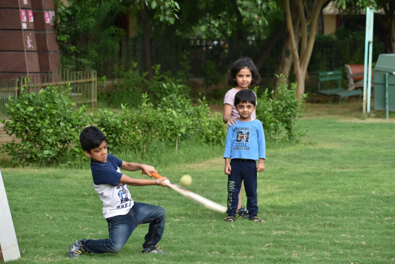 a boy is holding a baseball bat ready to hit the ball