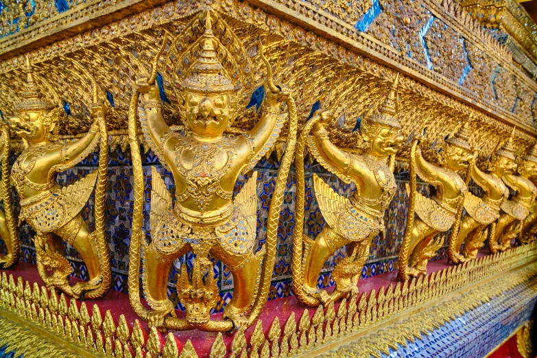 a gold wall with many golden designs and some ornate artwork