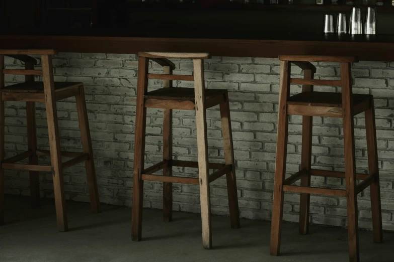 two wooden stools on a table in front of a brick wall