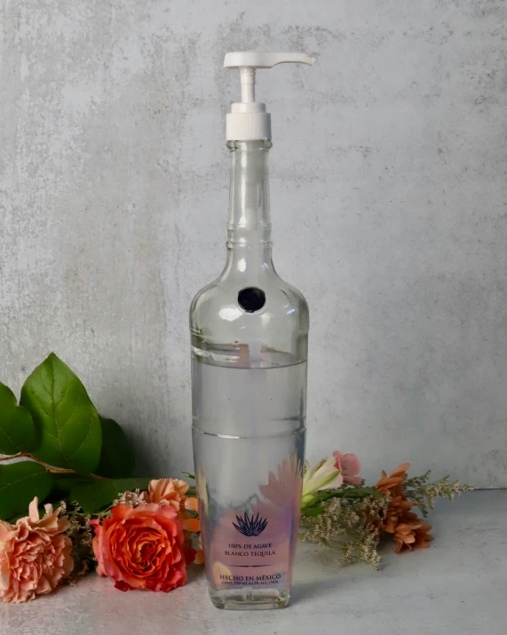 a bottle of liquid sitting next to flowers