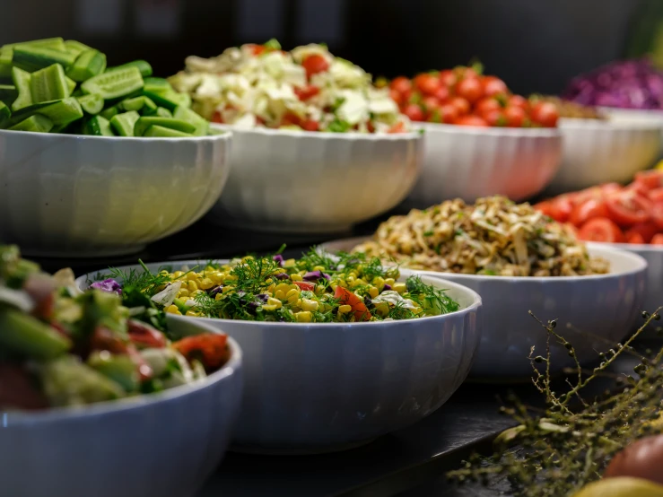 a buffet table filled with bowls filled with different kinds of vegetables