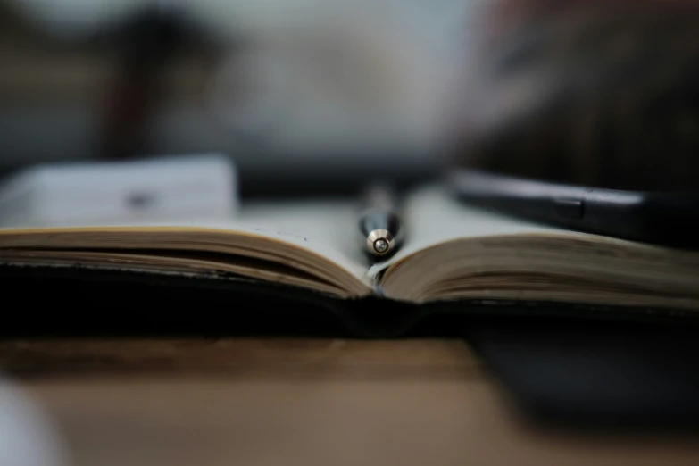 a closeup po of a book and pen on a table