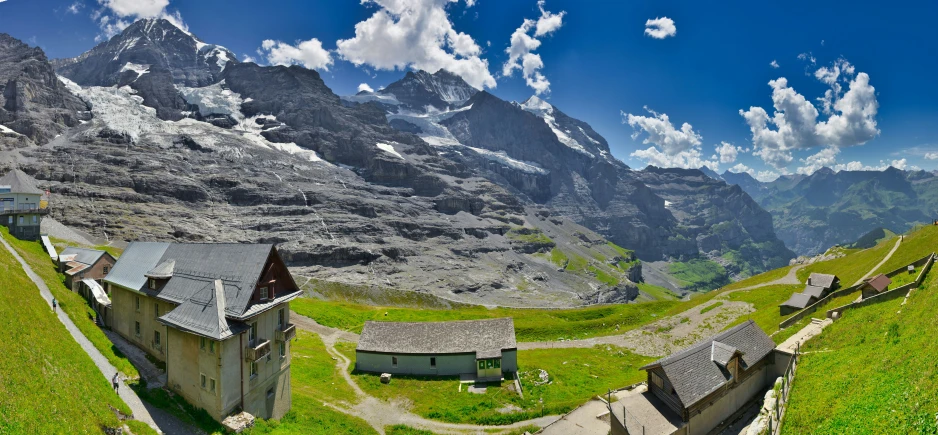 this house sits in the middle of the grass in front of mountains