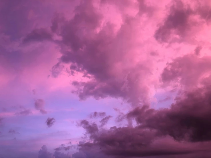 a plane is flying with purple clouds behind it