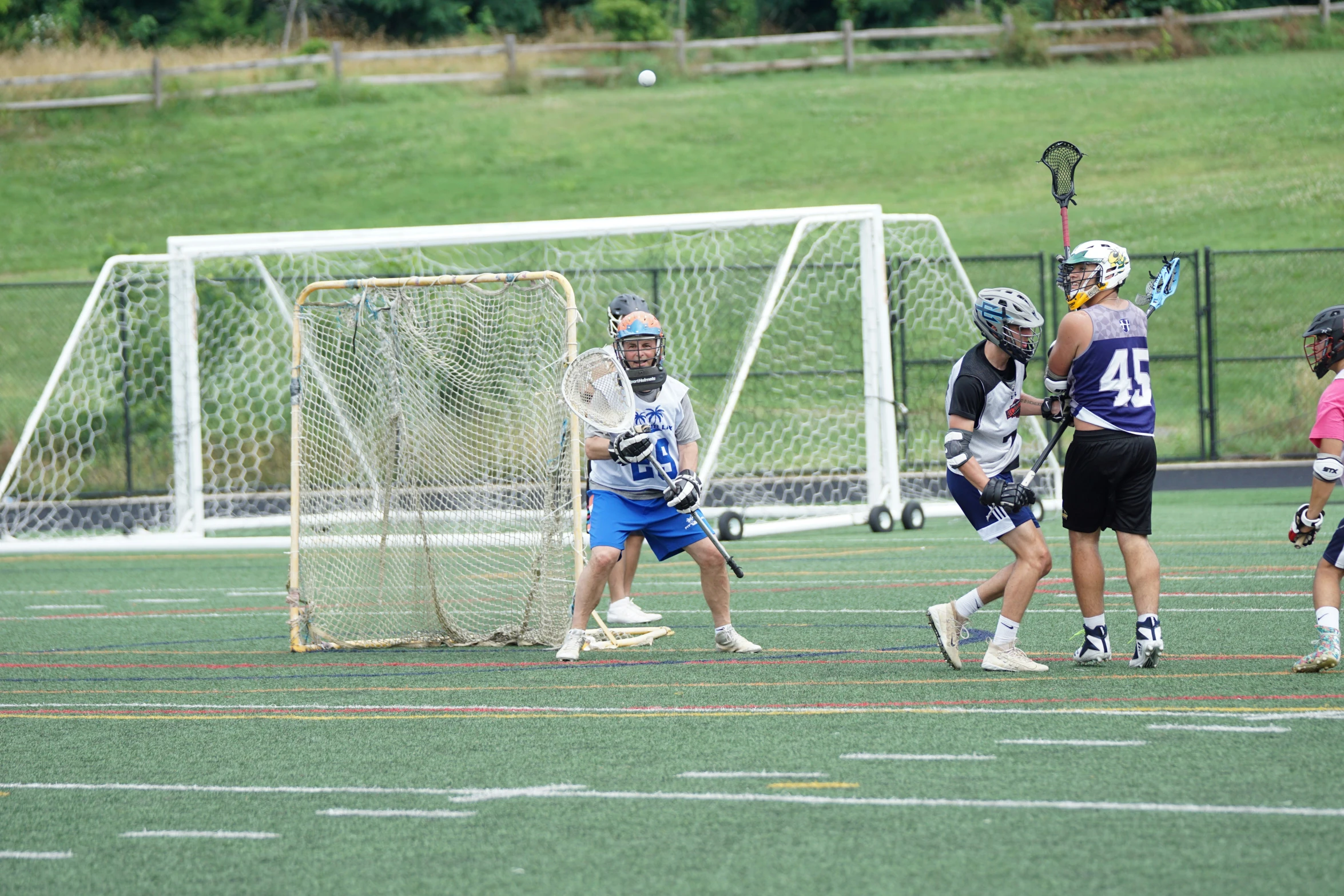 some s playing lacrosse on a field in front of a goal