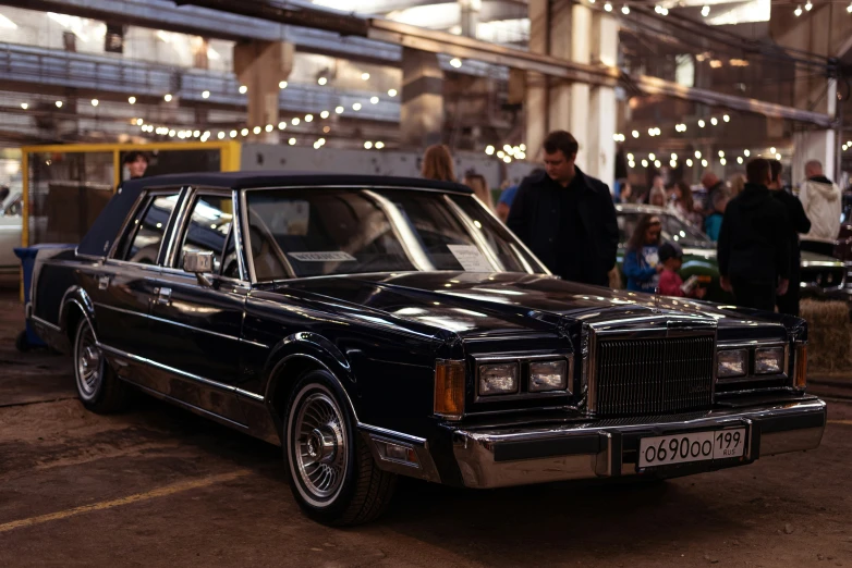 a vintage black car sits in front of a crowd