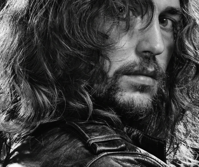 a man with long hair wearing leather is in profile
