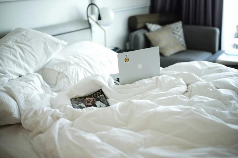 an open laptop is on top of a white blanket