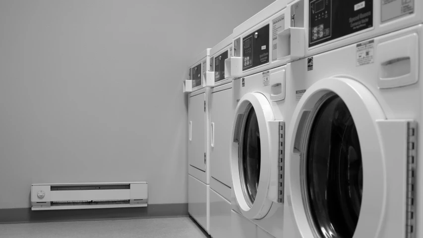 a row of washing machines and dryers against a wall