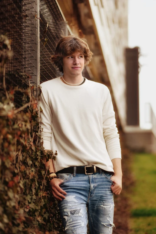 the young man is leaning against a fence