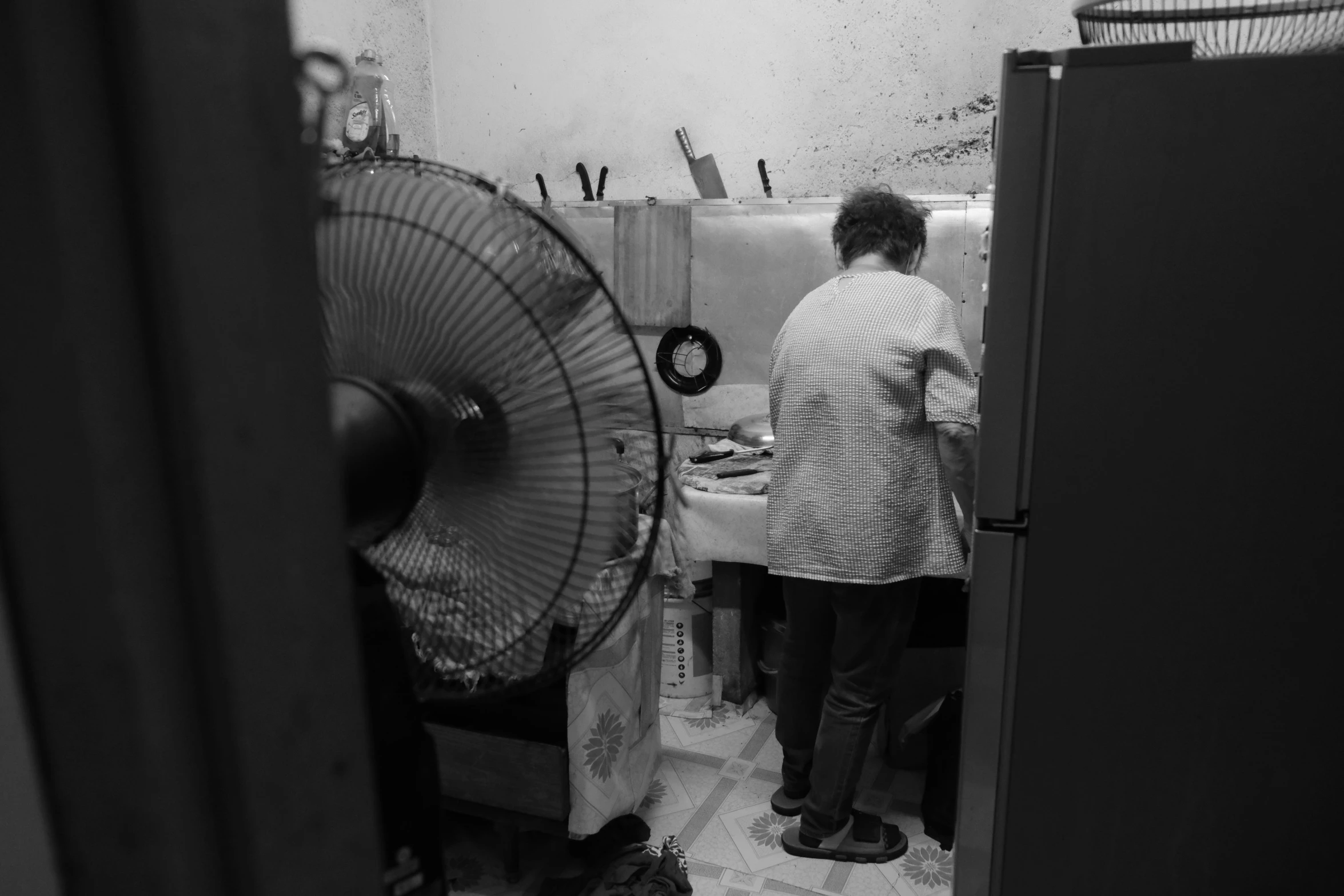 a woman standing in a room with an old fashioned fan