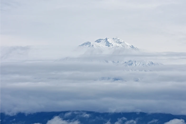 a large white mountain with clouds flying below it