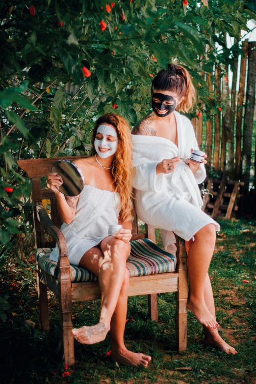 two girls sitting in a chair while one of them is painted white