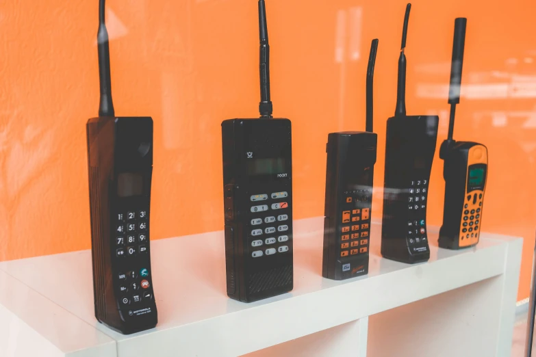 three telephones and two handsets sitting on top of a shelf