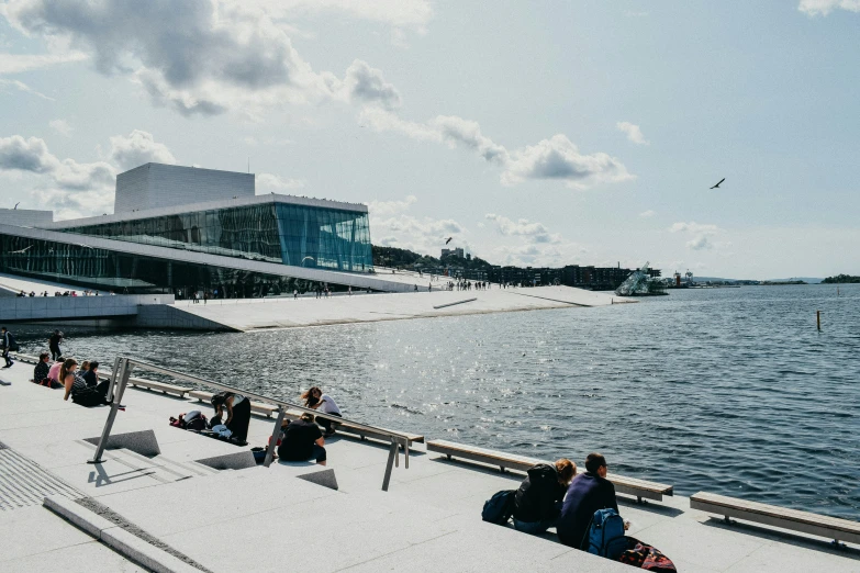 a large body of water with people sitting on it and standing in front of the water