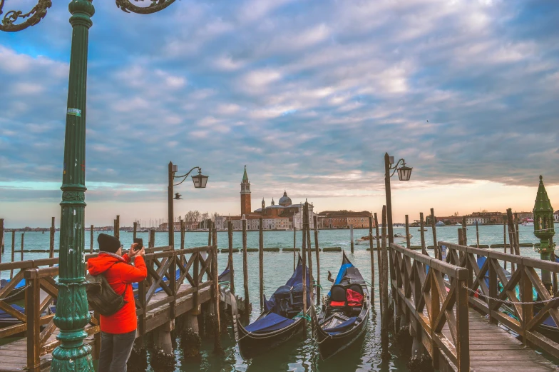 two people on a dock standing next to boats