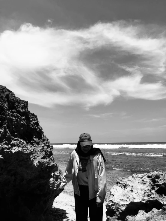 black and white pograph of woman standing near rocky area