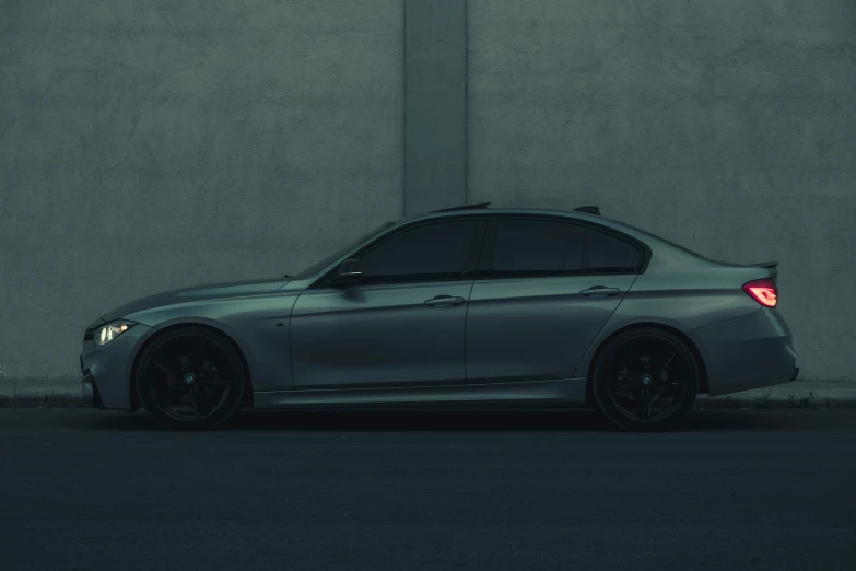 the rear of a silver car parked next to a wall